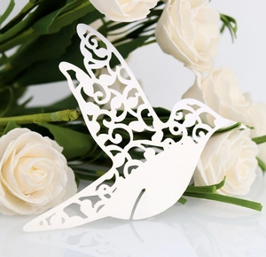 Détail macro d'un marque-place oiseau blanc découpé au laser sur des roses