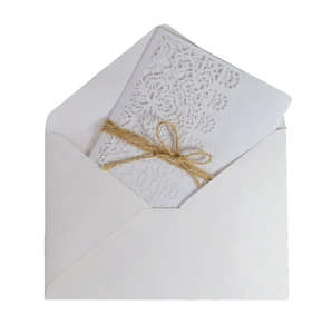 Laser cut white wedding invitation with lace pattern, jute twine, and matching envelope