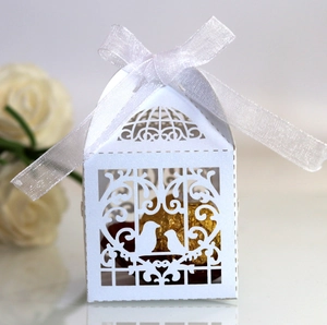 Detailed laser-cut white birdcage wedding favor box with a delicate ribbon and chocolate