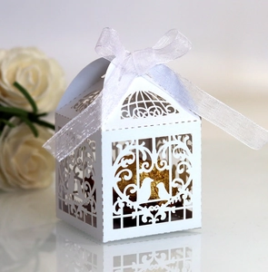 Close-up of laser-cut white wedding favor box with love birds and ribbon detail