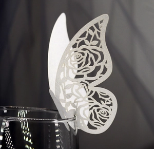 Detail of white laser-cut butterfly cup card with intricate rose patterns for weddings