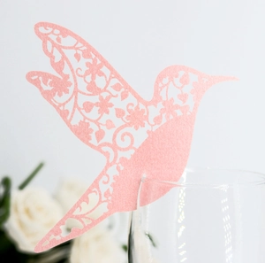 Detail der rosa lasergeschnittenen Kolibri-Platzkarte mit Blumenmuster auf einem Glas