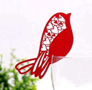 Macro detail of red laser-cut bird place card with heart pattern on a glass rim