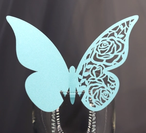 Detail of light blue laser-cut butterfly cup card with elegant rose hollow pattern