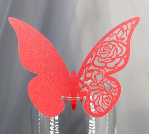 Detailed laser-cut rose pattern on a red butterfly wine glass card for wedding decor