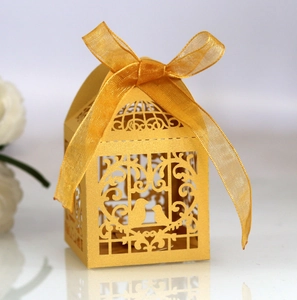 Detailed close-up of golden laser-cut birdcage candy box with elegant organza ribbon bow