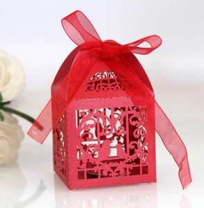 Detail of red laser-cut wedding favor box with bird patterns and a satin ribbon bow