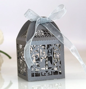 Detail of laser-cut wedding favor box with bird patterns and a blue satin ribbon bow