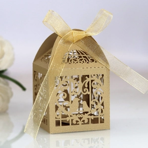 Detail of laser-cut wedding candy box with golden bird design and ribbon bow