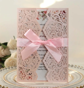 Macro detail of pink laser-cut wedding invitation with pearl paper and silk ribbon