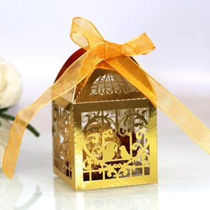 Golden laser-cut birdcage favor box with orange ribbon and chocolate inside for weddings