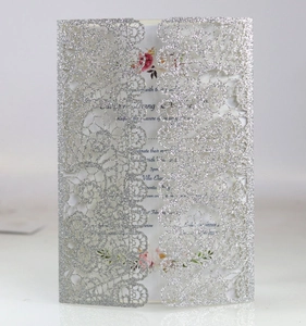 Detail of silver glitter laser-cut lace wedding invitation with floral inner card