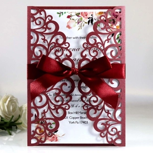 Navy blue laser cut wedding invitation with elegant red satin bow and floral inner card