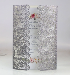 Detail of silver glitter laser-cut lace wedding invitation with floral white insert card