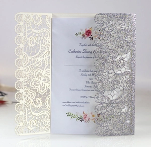 Detail view of laser-cut wedding invitation with silver glitter lace and floral inner card