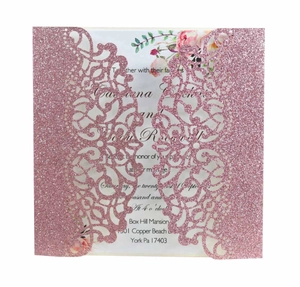 Macro shot of laser-cut wedding invitation featuring intricate pink glitter floral patterns