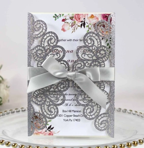 Détail de l'invitation de mariage argentée pailletée avec découpe laser et nœud