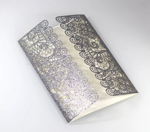 Macro view of silver glitter laser-cut floral lace wedding invitation card cover