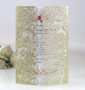 Detail of laser-cut gold glitter wedding invitation with intricate lace hollow pattern