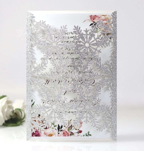 Detail of laser cut silver glitter snowflake invitation card with white floral inner page