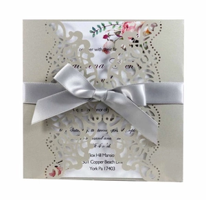 Detail of laser-cut champagne gold wedding invitation with silver ribbon and floral insert