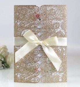 Laser-cut glitter gold hollow wedding invitation card with elegant cream ribbon bow