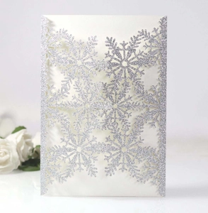 Detailed laser-cut silver glitter snowflake invitation card with intricate hollow patterns