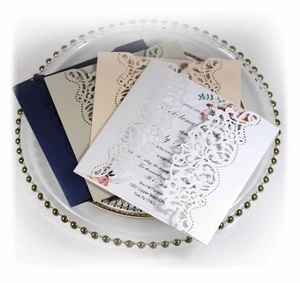 Detail of laser cut wedding invitations in white and navy blue on a glass tray