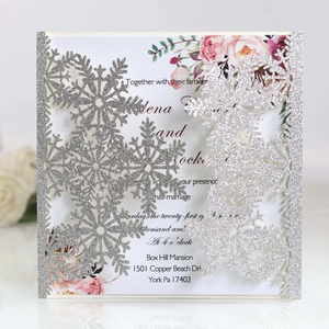 Close-up of laser-cut silver glitter snowflake invitation with floral inner card