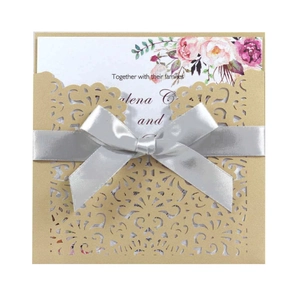 Detailed laser-cut hollow pattern on champagne wedding invitation with silver satin bow