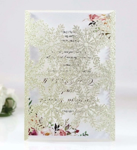 Detailed laser-cut gold glitter snowflake pattern on elegant wedding invitation cards
