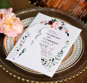 Détail de faire-part de mariage découpé au laser avec silhouette et carte fleurie rouge