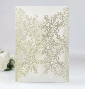 Detail of silver glitter laser-cut Christmas invitation featuring intricate snowflake designs