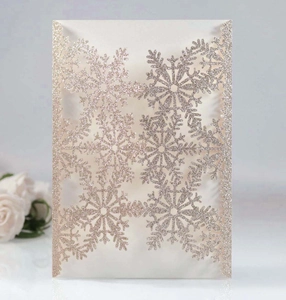 Macro detail of laser-cut snowflake hollow on white glitter paper invitation card