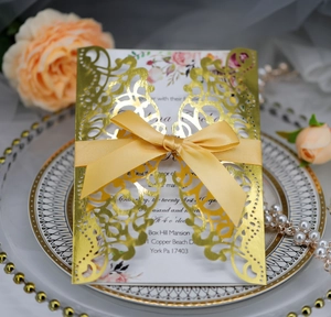 Elegant gold laser cut wedding invitation card with yellow ribbon on decorative ceramic plate