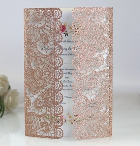 Close-up of rose gold laser-cut lace wedding invitation card with glitter finish