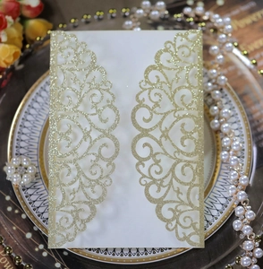 Detail of laser cut wedding invitation with gold glitter patterns on white cardstock
