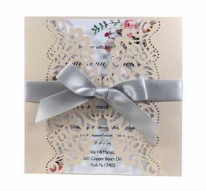 Champagne laser cut wedding invitation with white floral insert and silver satin bow