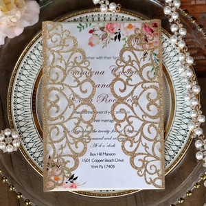 Detailed laser-cut glitter gold wedding invitation featuring intricate vine hollow patterns