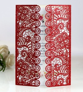 Detail of red glitter laser cut wedding invitation with floral patterns and white insert