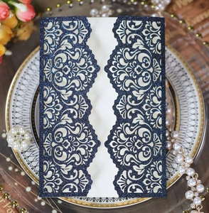 Macro shot of dark blue glitter laser-cut wedding invitation with elegant floral lace pattern