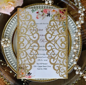 Detail of laser-cut gold glitter wedding invitation with floral inner card and pearls