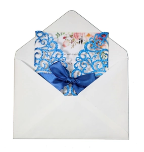 Detail of glitter laser cut navy wedding invitation with floral insert and satin bow