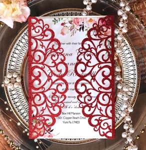 Detail of red laser-cut wedding invitation with gold glitter finish and floral inner card
