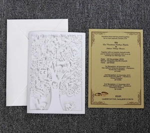 Detail of laser-cut tree and owl patterns on a white wedding invitation with gold card