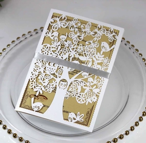 Detail of laser-cut wedding invitation featuring tree patterns and silver ribbon bow