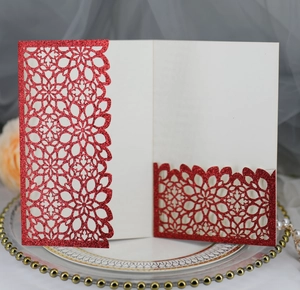 Détail de papier pailleté rouge avec motifs floraux découpés au laser et insert blanc
