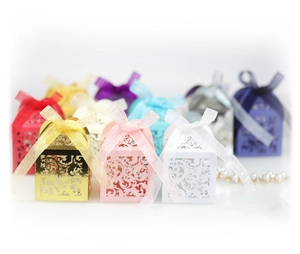 Laser cut favor boxes with intricate vine patterns and elegant satin ribbons for weddings