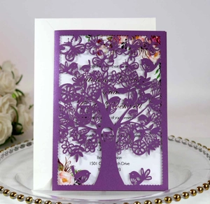 Detail of laser-cut purple wedding invitation featuring tree, bird and butterfly patterns