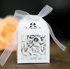 Elegant white laser-cut wedding favor box with floral patterns and a sheer ribbon bow